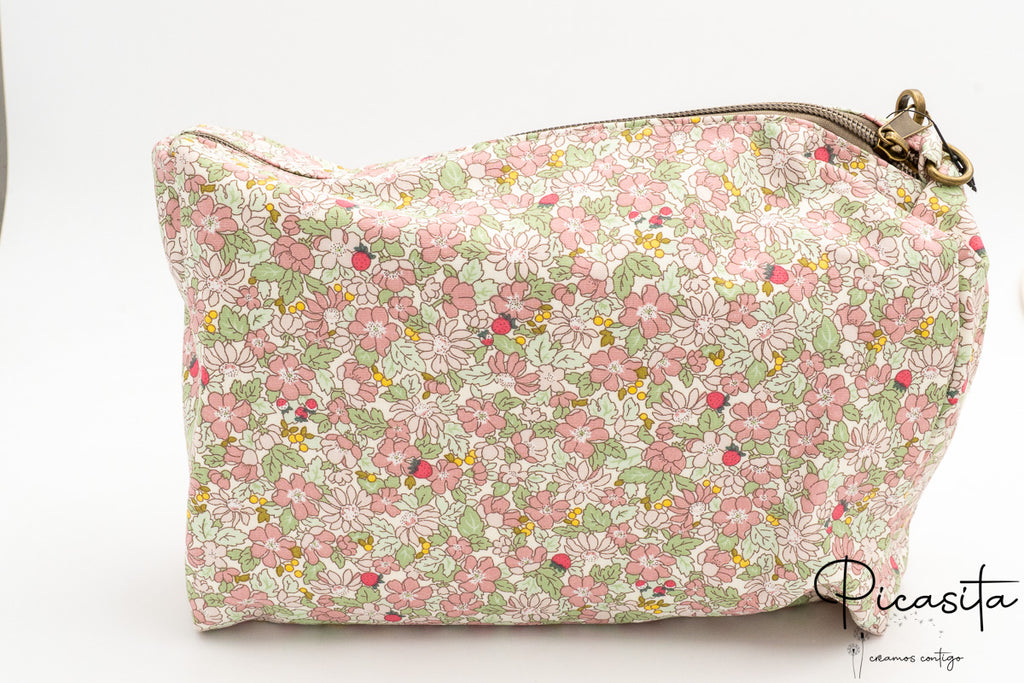 Detalle de neceser floral rosa con cierre de cremallera metálica y tirador de tela.