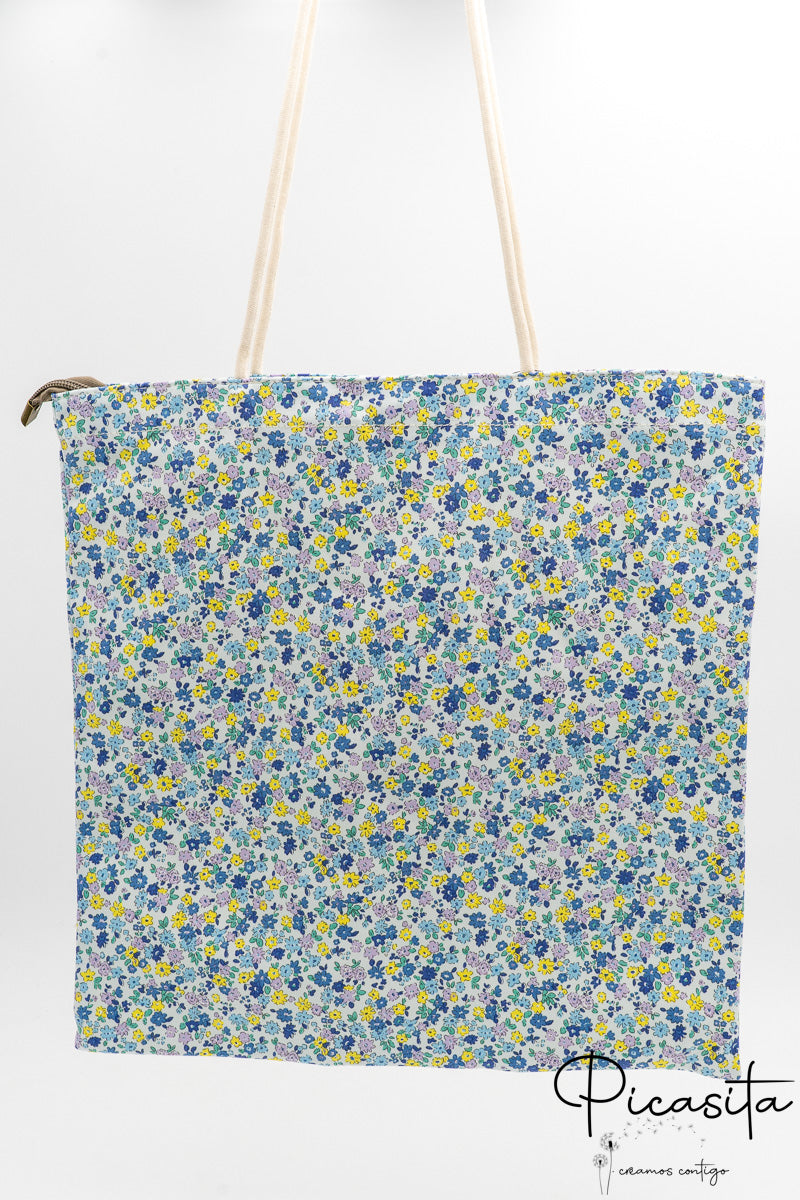 Bolsa de algodón con estampado floral azul y blanco con asas largas de cuerda.
