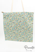 Bolsa tote con estampado de flores verdes y blancas colgada verticalmente mostrando su capacidad.