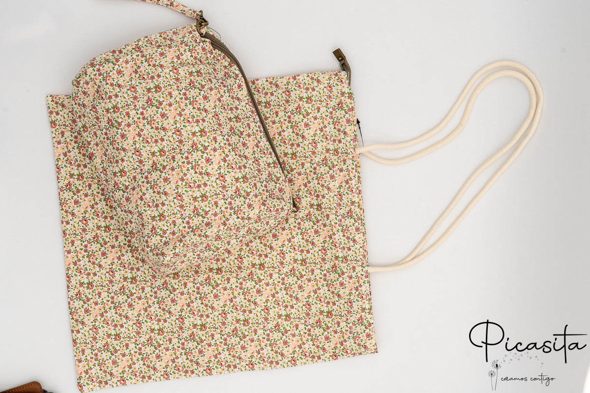Neceser sobre bolsa de tela con estampado de flores en color melocotón y hojas verdes.