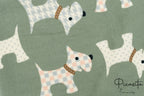 Primer plano de toalla verde oliva con estampado de perritos en tonos pastel.