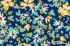 Primer plano de toalla azul marino con flores blancas y amarillas estampadas.
