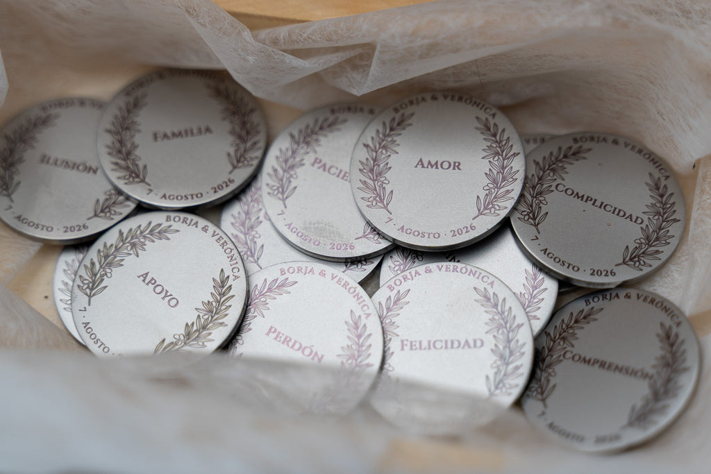 Detalle de monedas de boda grabadas con palabras como amor, familia y perdón.