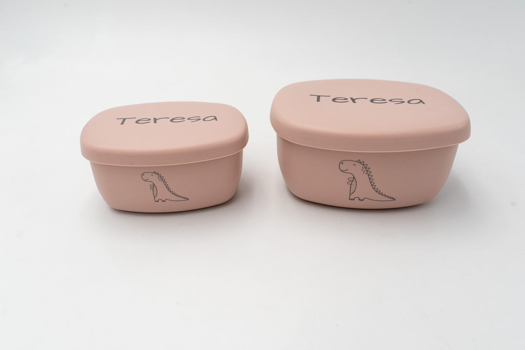 Dos tuppers rosa personalizados con el nombre Teresa y dibujos de dinosaurio