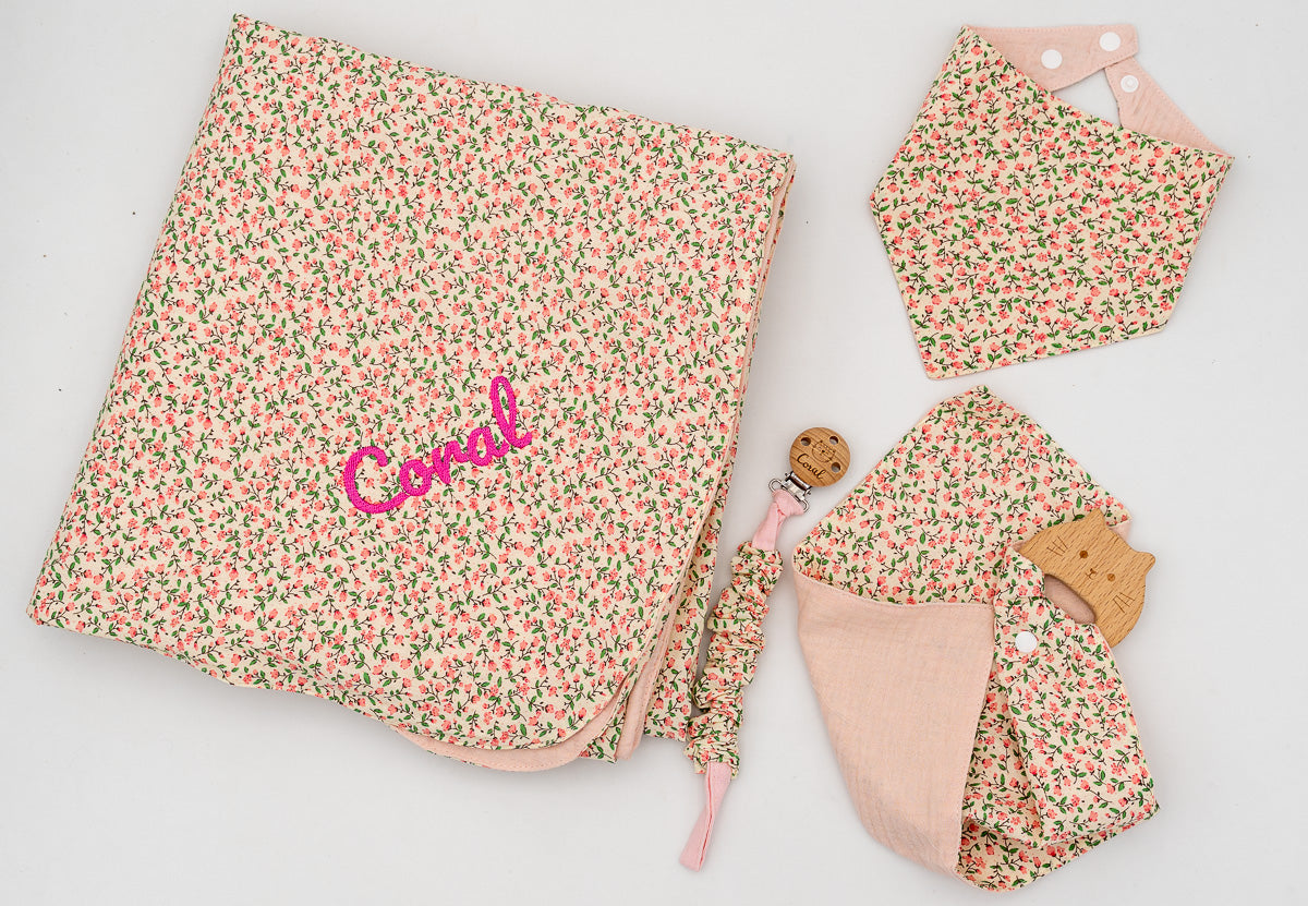 Pink set with a floral blanket embroidered with the name Coral, bandana bib, pink muslin square with a wooden teether and dummy clip.