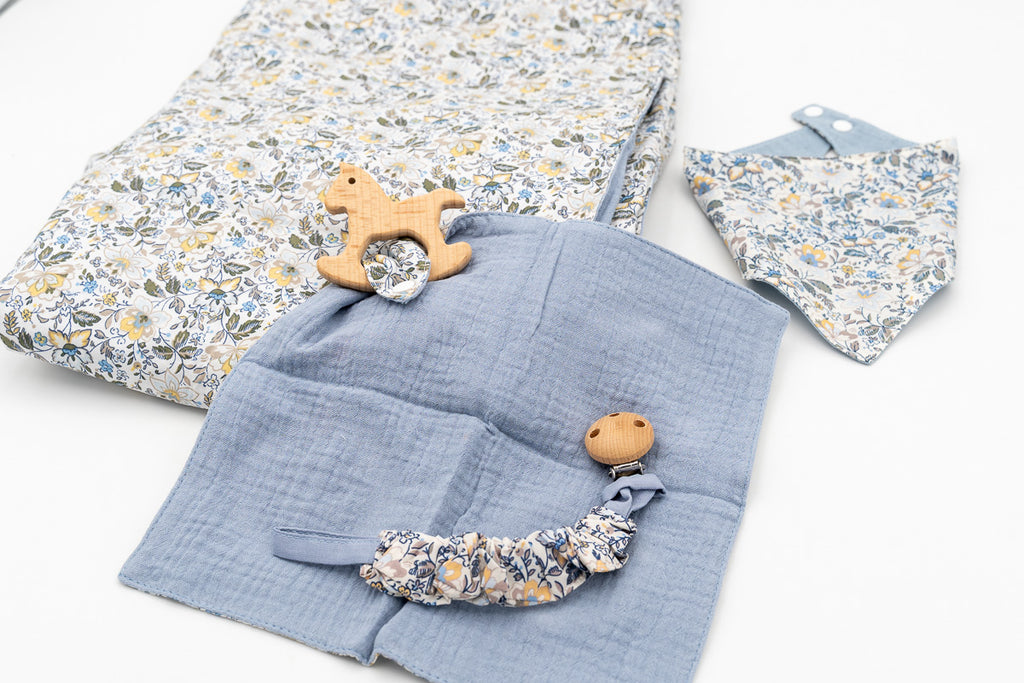 Blue set with a floral blanket, bandana bib, blue muslin square with a wooden rocking horse teether and a dummy clip with a wooden clasp.