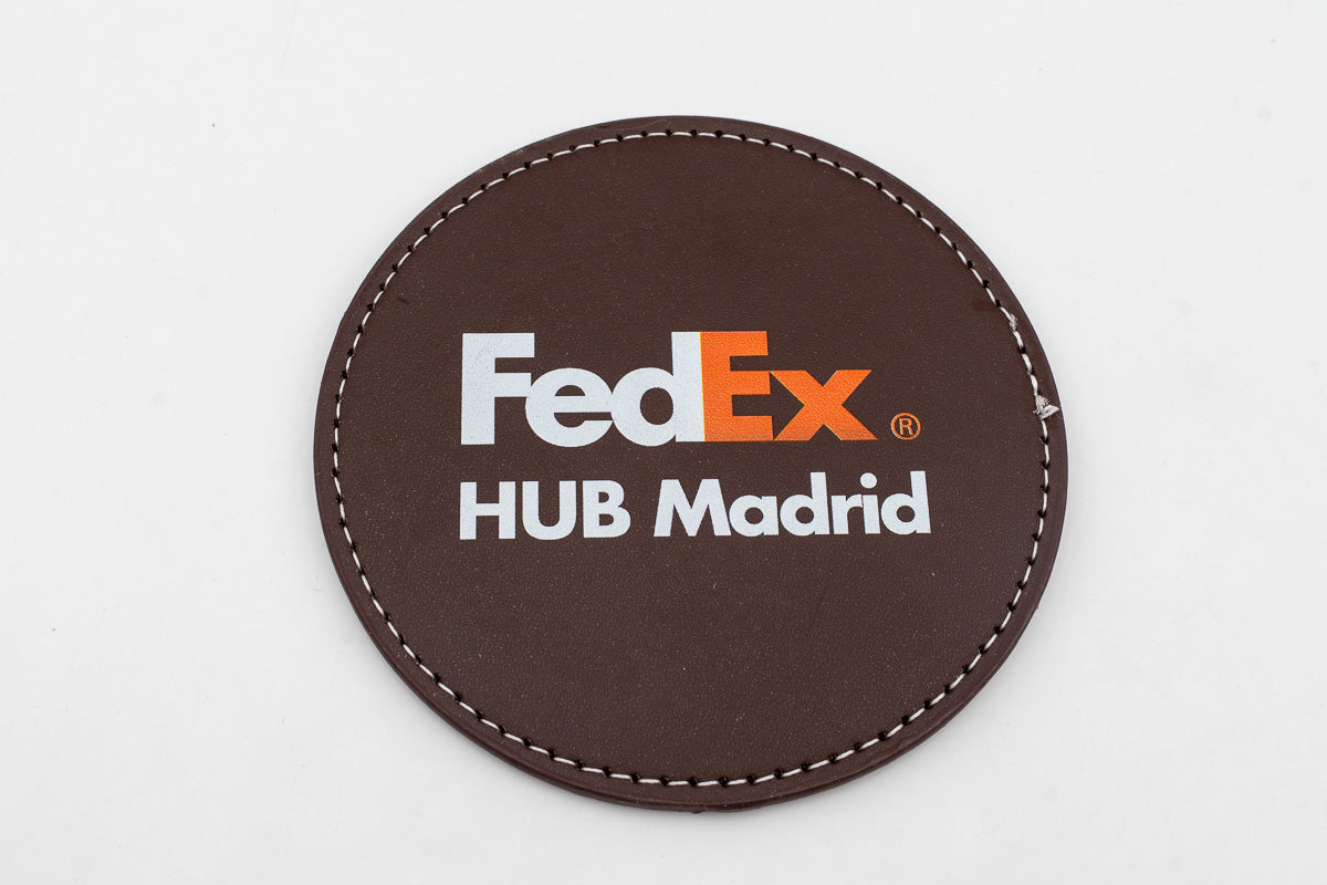 Round brown coaster with a colour FedEx logo.