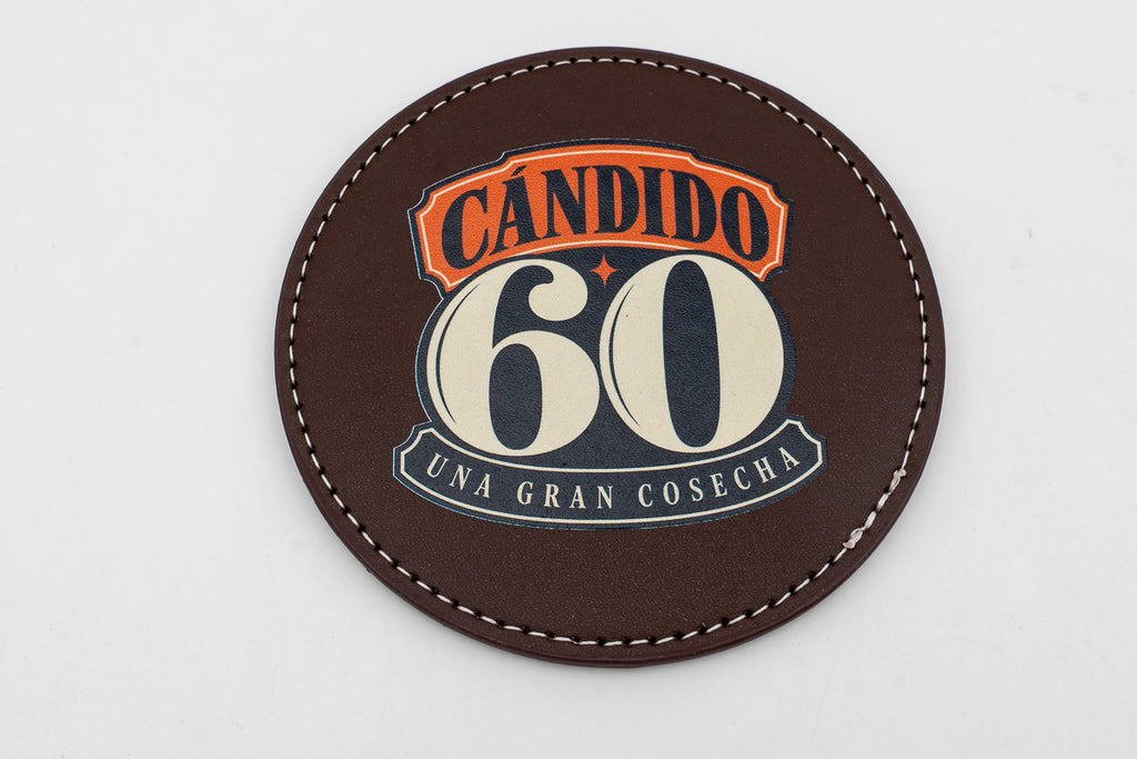Round brown coaster with a colour Cándido 60 birthday design.