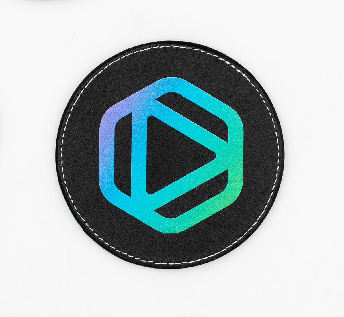 Round black coaster with a blue and green geometric emblem.