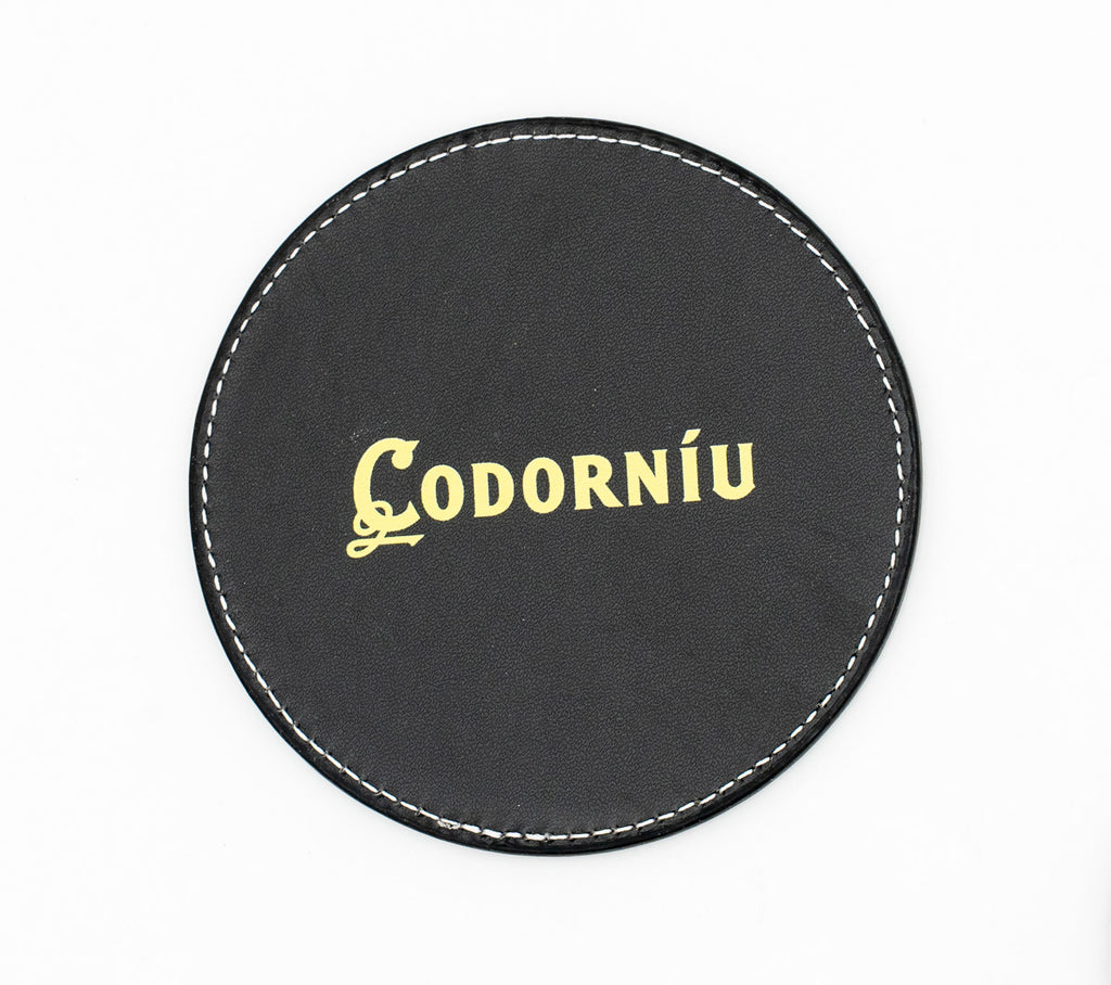 Round black coaster with a gold-coloured Codorníu logo.