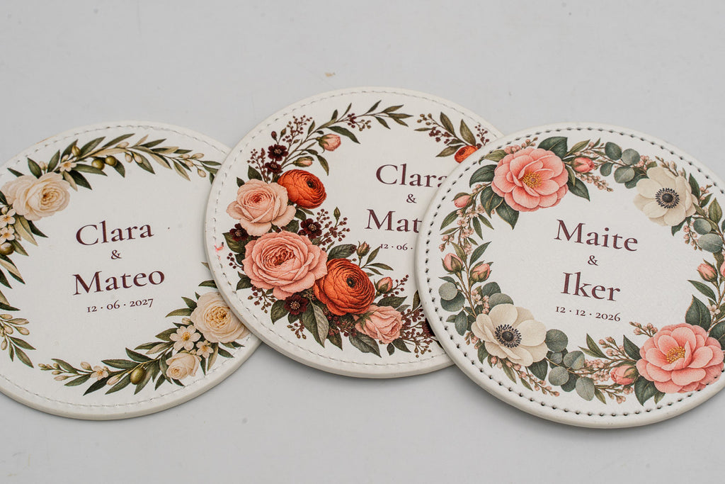 Three round white coasters with colourful flowers and couples’ names.
