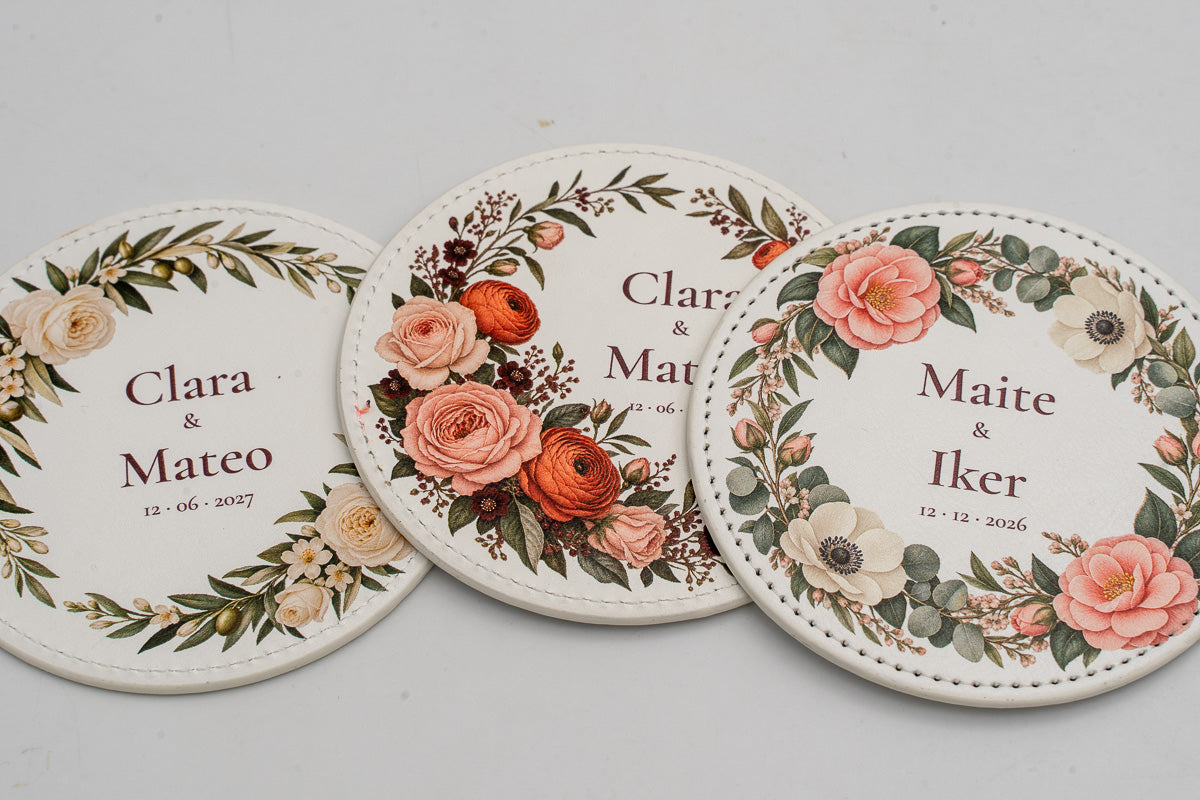 Three round white coasters with colourful flowers and couples’ names.