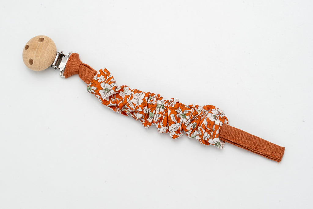 Gathered fabric dummy clip with flowers on a terracotta background and a wooden clip