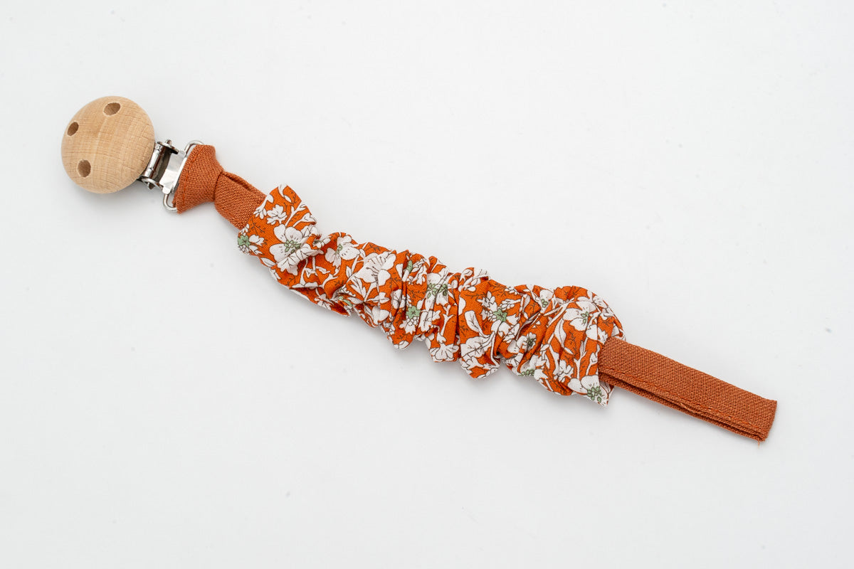 Gathered fabric dummy clip with flowers on a terracotta background and a wooden clip