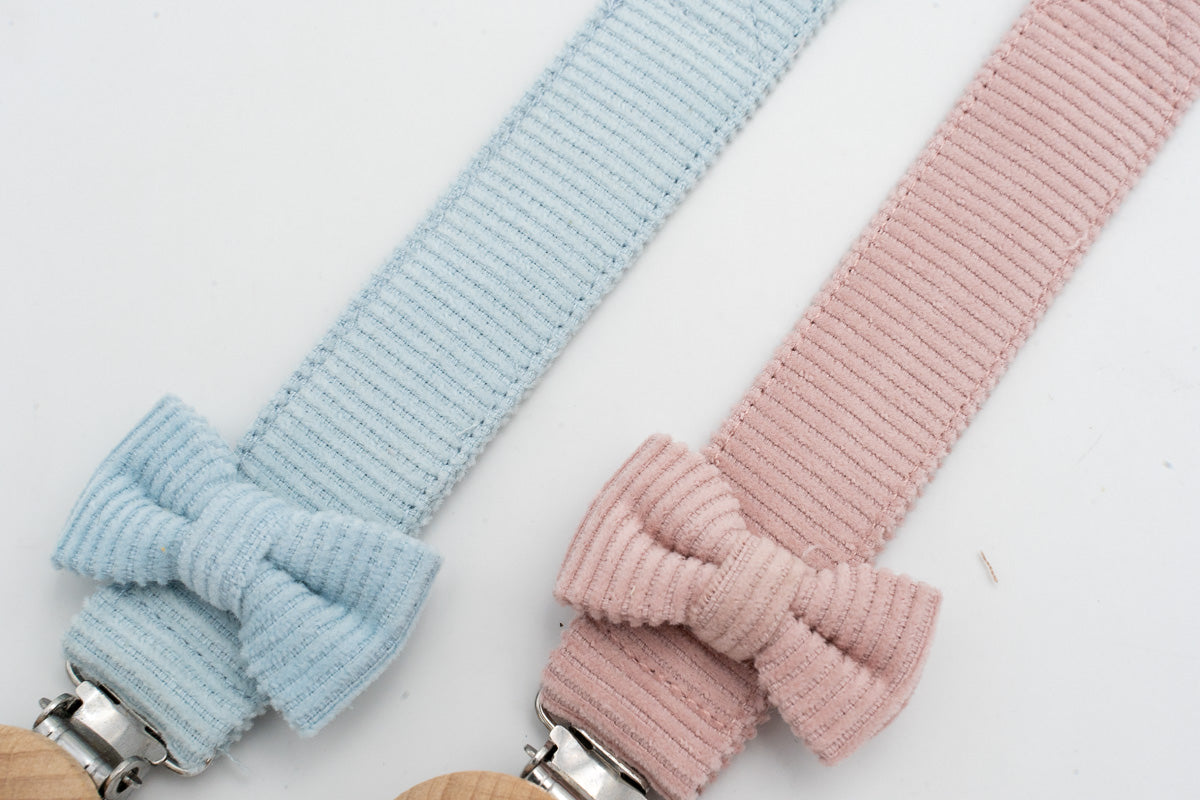 Close-up of light blue and pink bow dummy clips beside their wooden clips