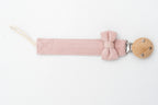 Pink dummy clip with a bow beside the round wooden clip