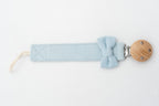 Light blue dummy clip with a bow beside the round wooden clip