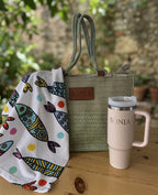 Bolso de rafia verde con nombre Sonia grabado y toalla blanca con estampado de peces.