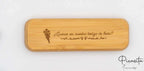 Estuche de bambú cerrado con grabado láser de flores y frase de agradecimiento sobre fondo blanco.