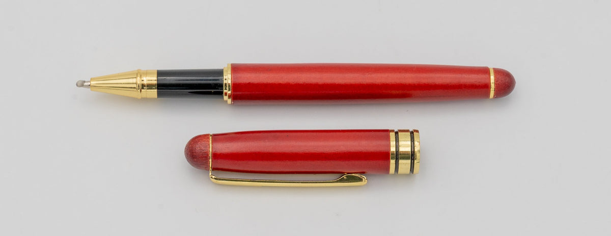 Reddish wooden pen with its cap removed and gold-coloured details.