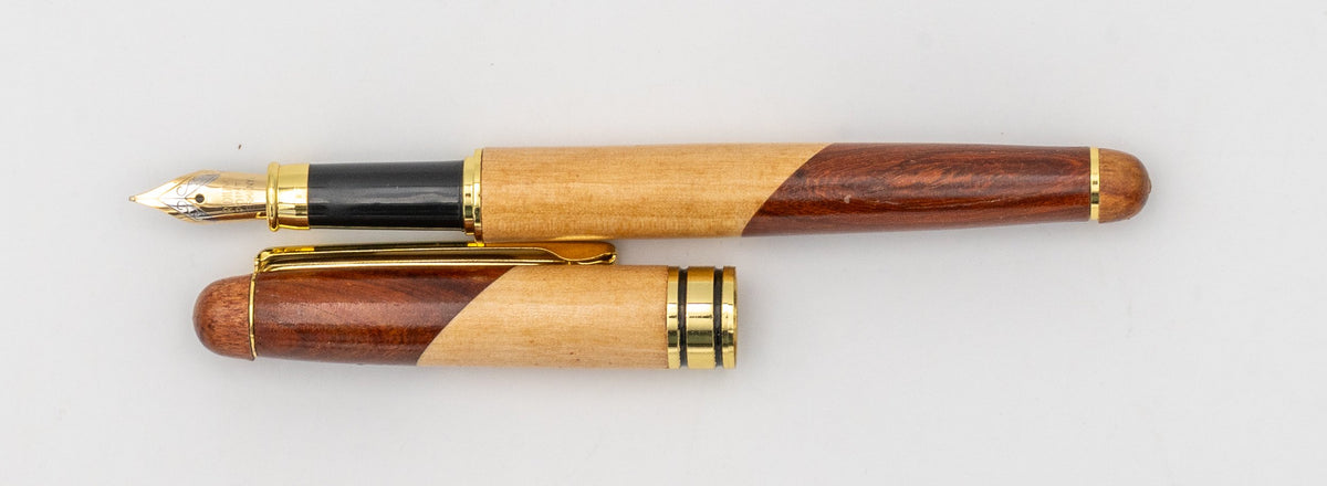 Two-tone wooden fountain pen with its cap removed and its nib visible.