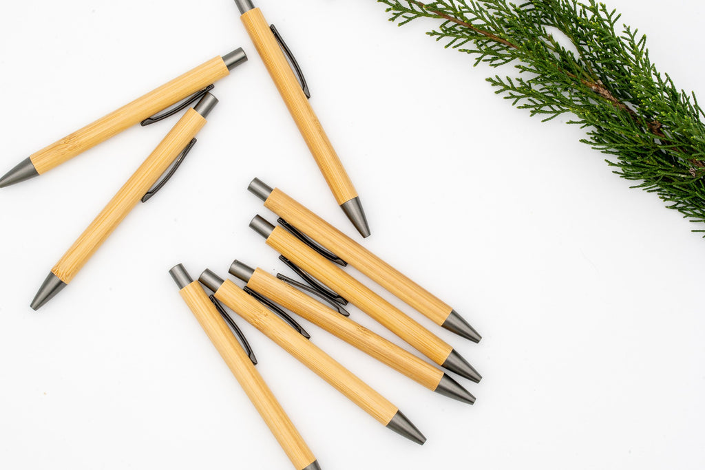 Bamboo pens with grey clips, push buttons and tips on a white background.
