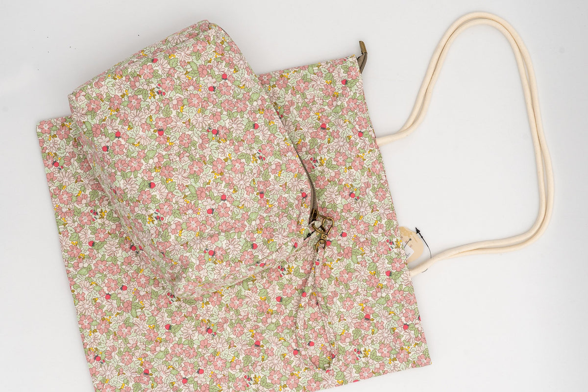 Wash bag and cotton bag with a pink and green floral print on a white background.