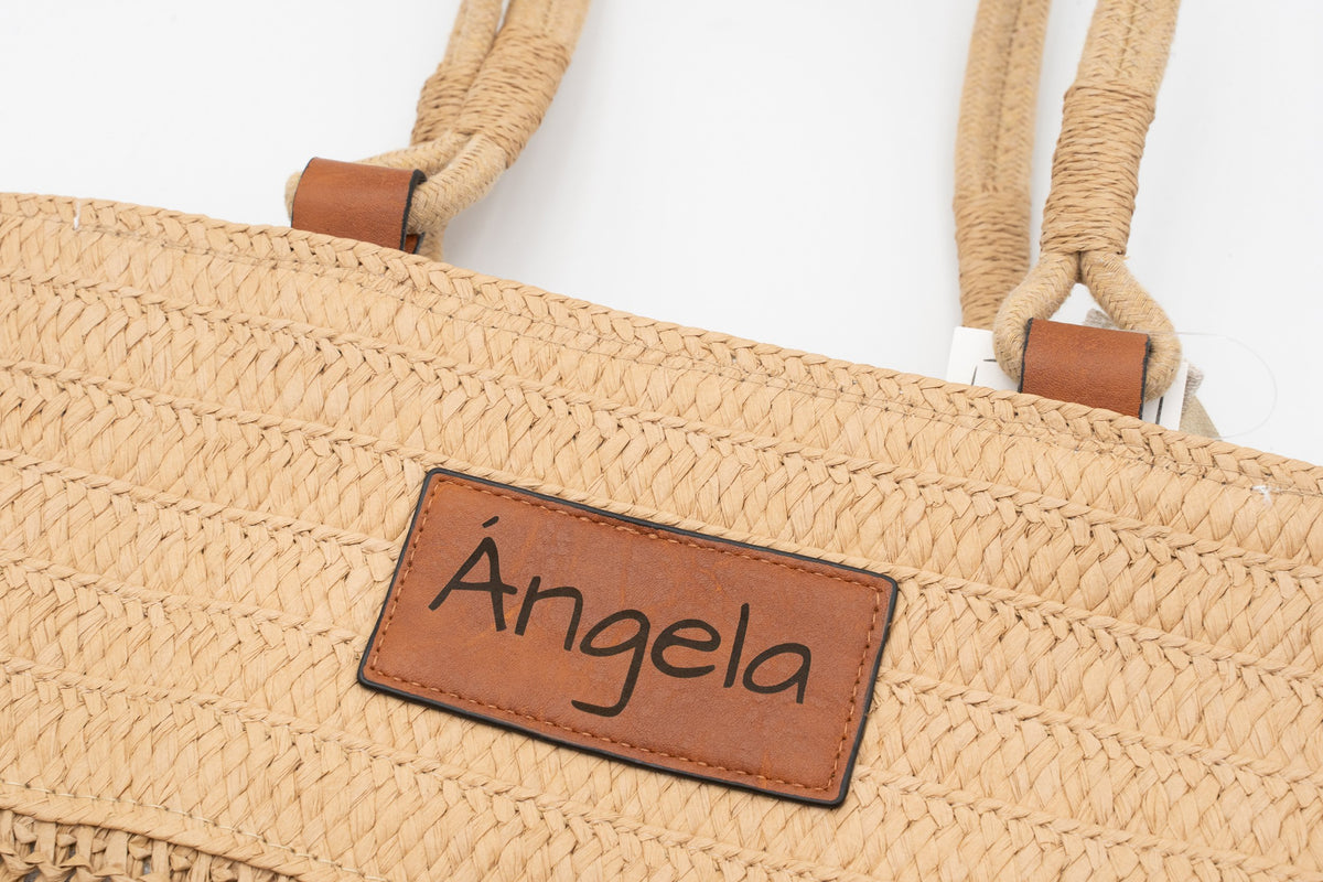 Faux leather patch of a raffia bag engraved with the name Ángela