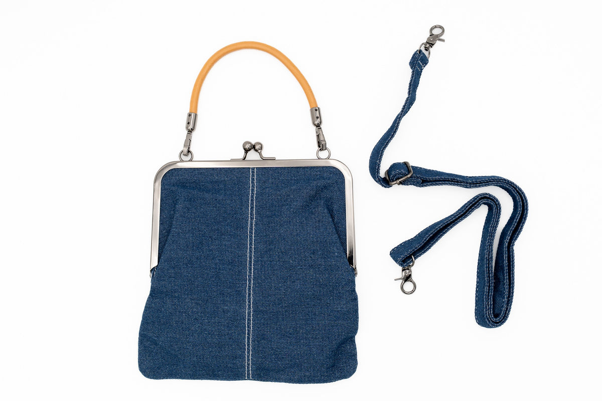 Denim handbag with a metal frame clasp and short ochre handle