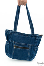Bolso denim con bolsillos laterales elásticos y un bolsillo frontal con cremallera horizontal.