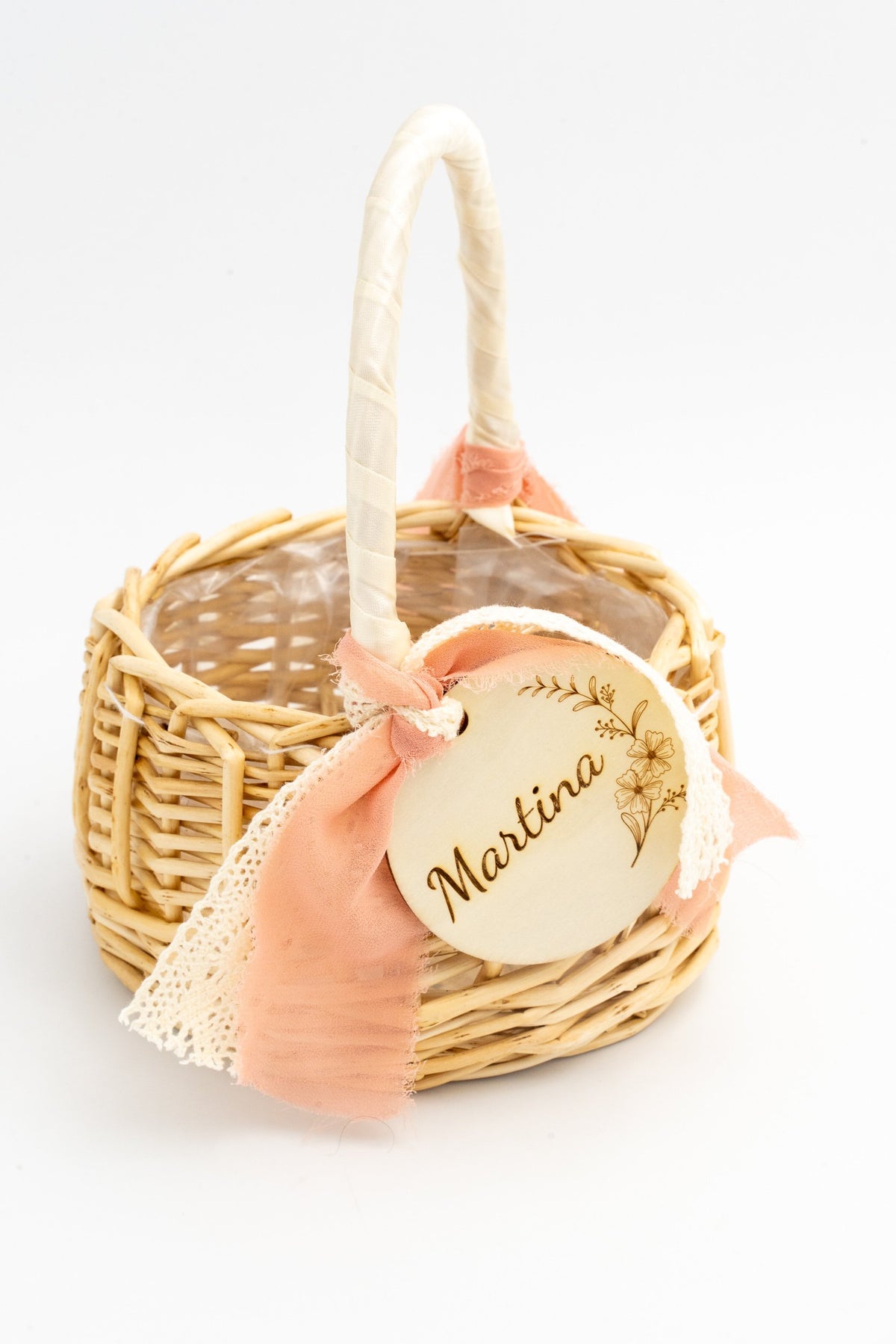 Rattan basket with a cream ribbon-wrapped handle and salmon-coloured gauze bow.