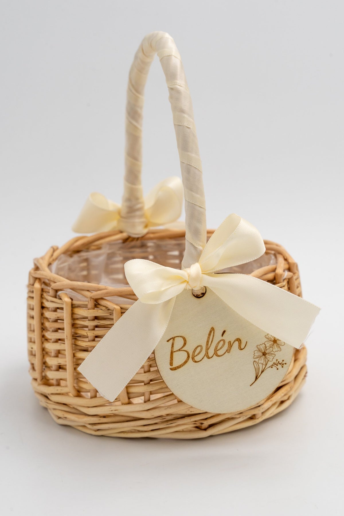 Handcrafted natural-fibre basket with a cream bow and botanical detail on a wooden disc.