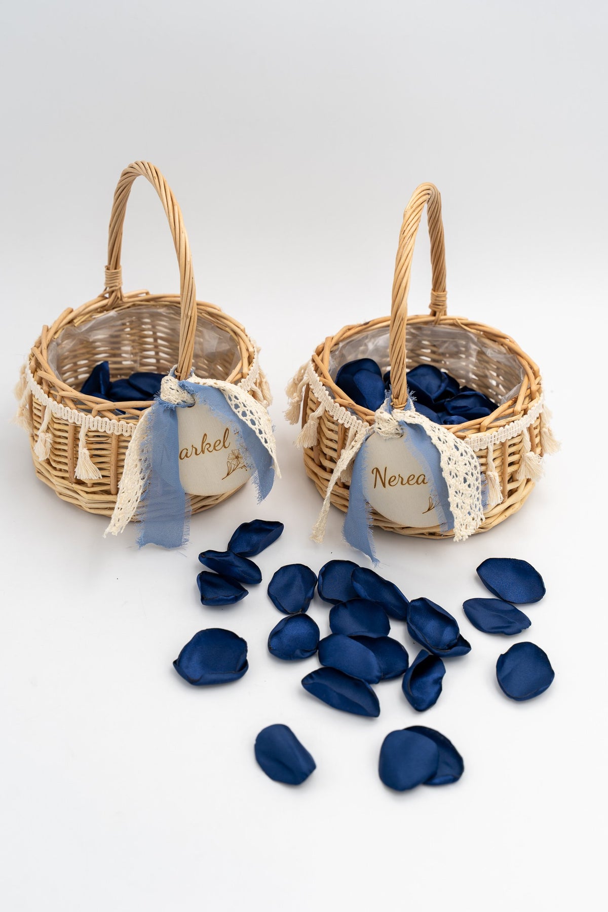 Two small rattan flower girl baskets surrounded by navy blue petals