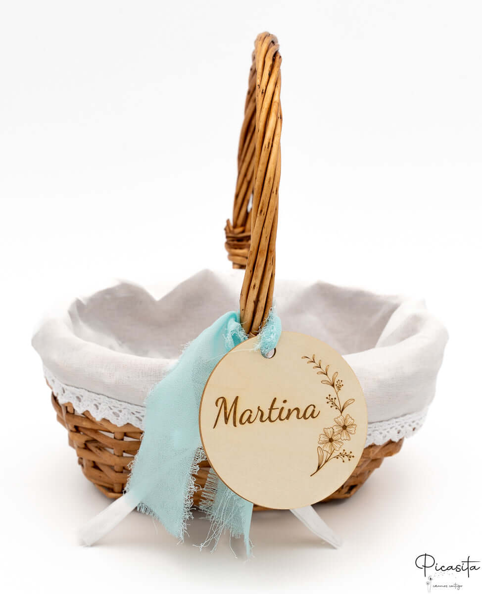 Cesta de mimbre con forro de tela blanca, encaje y lazo de color azul claro.