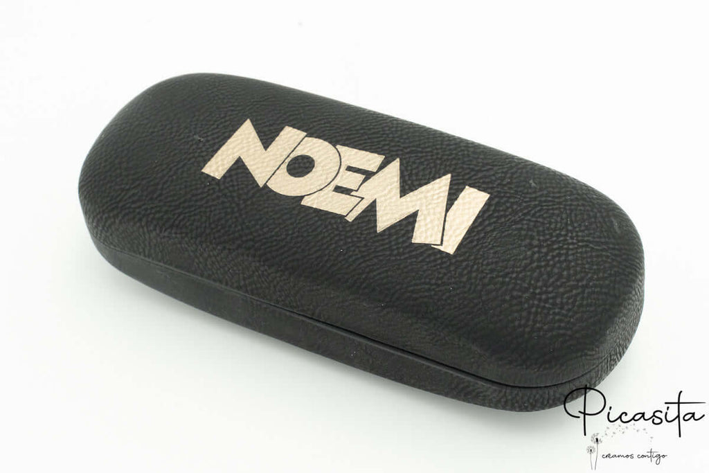 Funda rígida negra con textura de piel y nombre Noemi grabado en dorado.