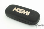 Funda rígida negra con textura de piel y nombre Noemi grabado en dorado.