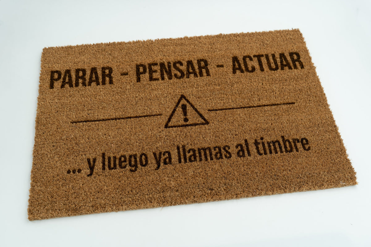 Felpudo con frase original y símbolo de advertencia grabado en fibra natural de coco.