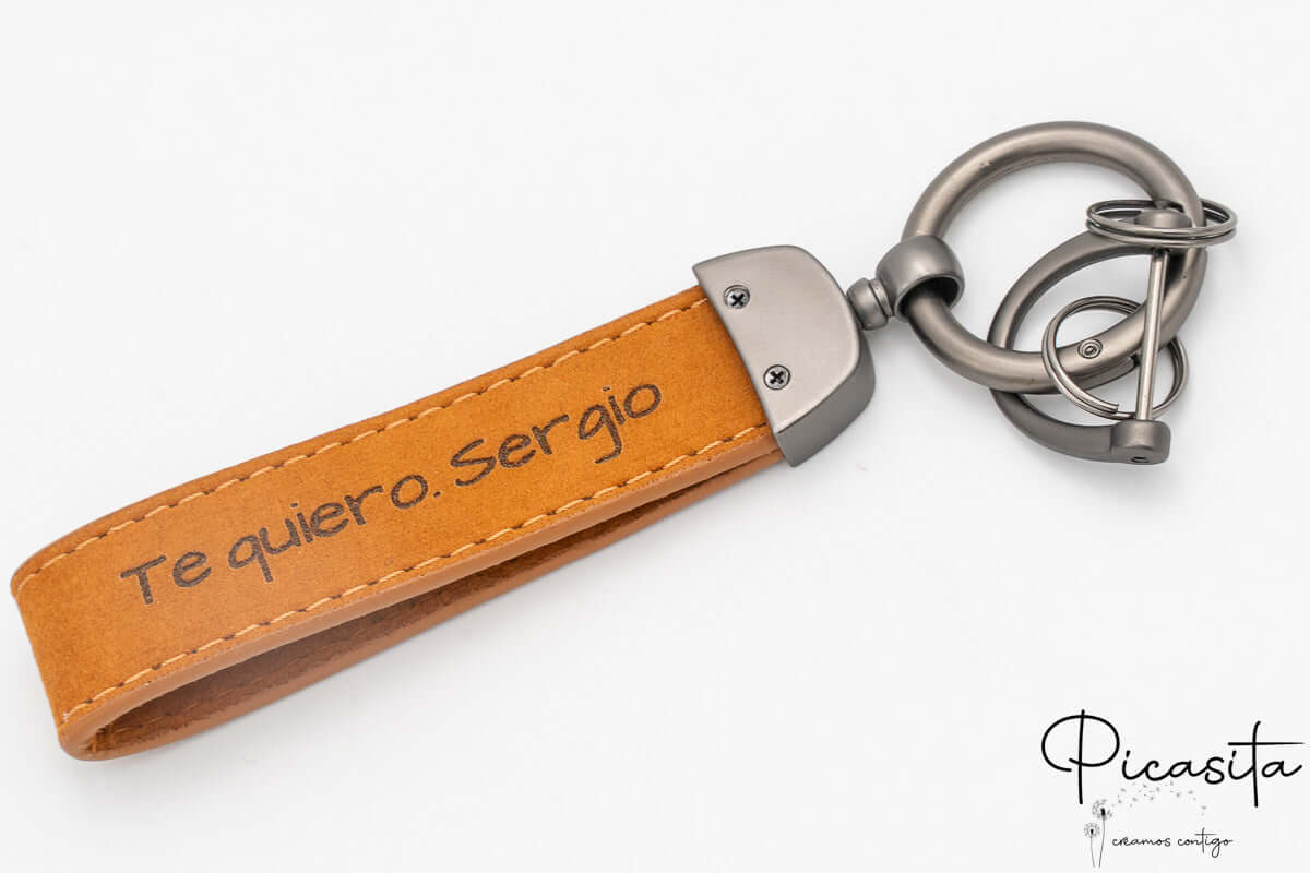 Reverso de llavero de cuero personalizado con frase grabada y tornillos de fijación metálicos.