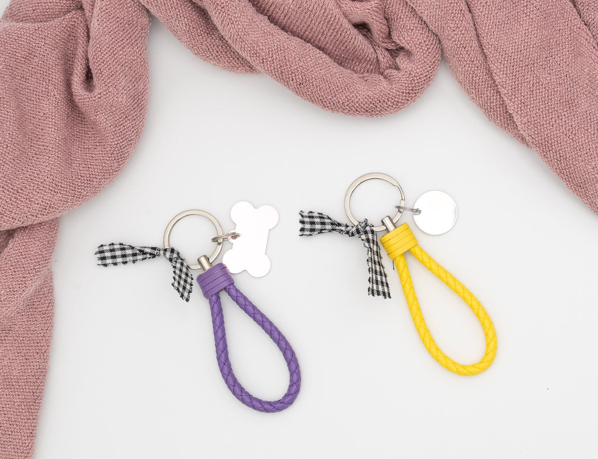 Purple and yellow braided faux-leather keyrings with metal tags and a gingham bow