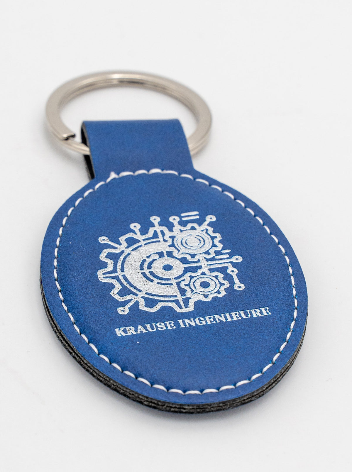 Blue oval keyring with a light logo and white stitching.