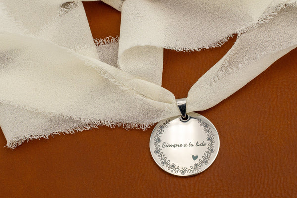 Mirror-finish steel charm with the phrase “Always by your side” and a floral border, tied with an ivory chiffon ribbon