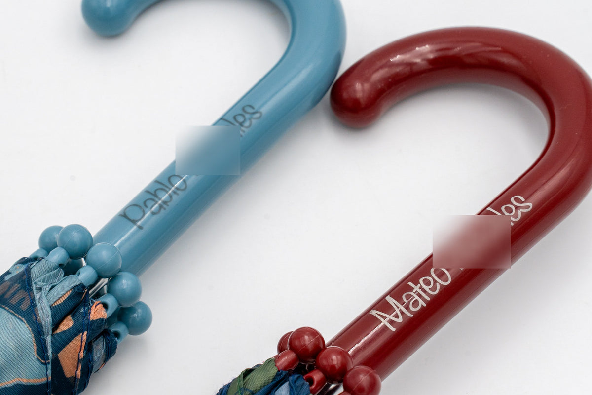 Blue and burgundy children's umbrella handles with the children's names printed on them