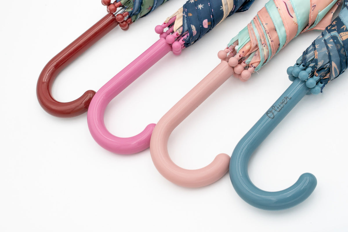 Four children's umbrella handles in burgundy, dark pink, light pink and blue