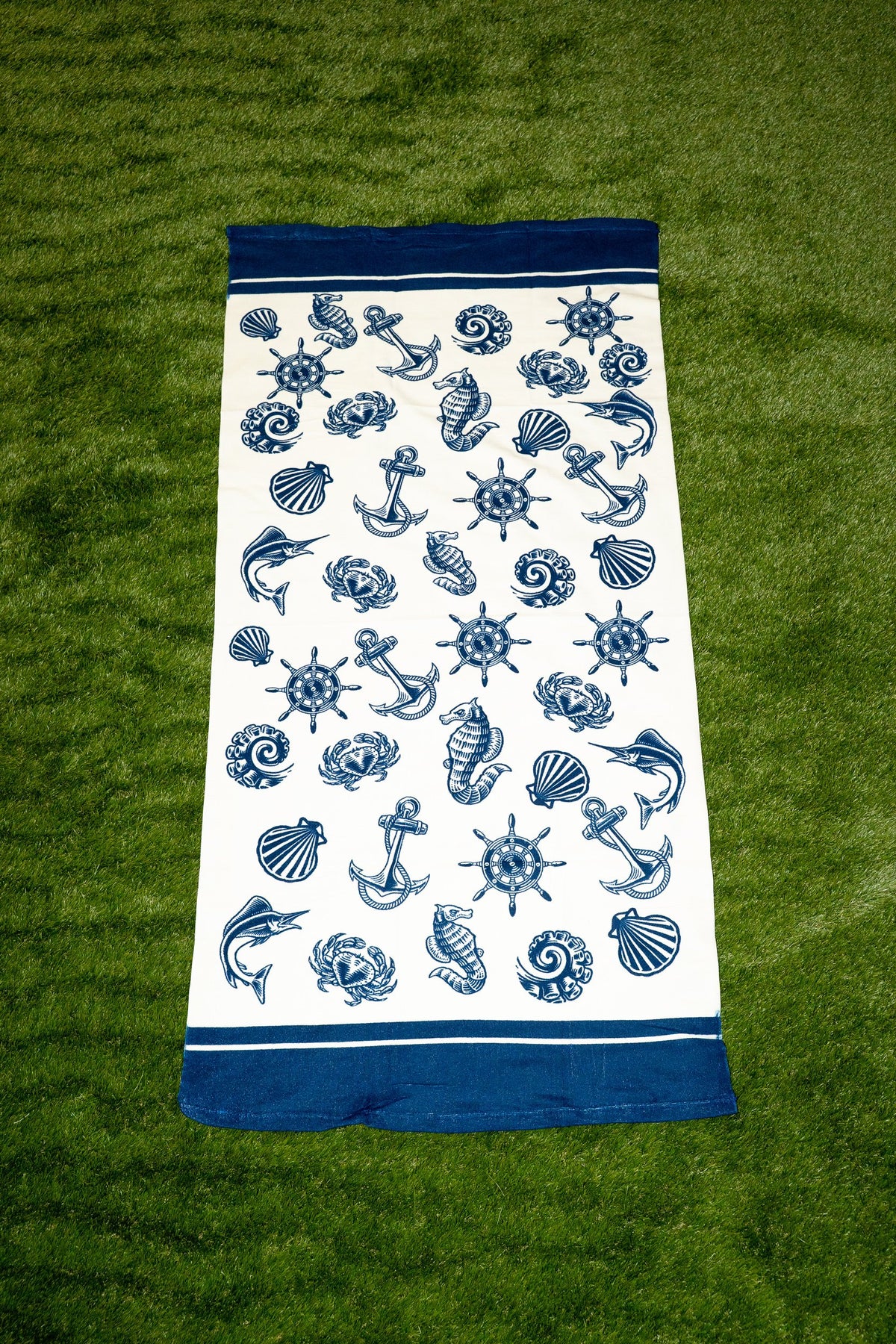 White towel with a blue nautical print of anchors, shells and ship's wheels