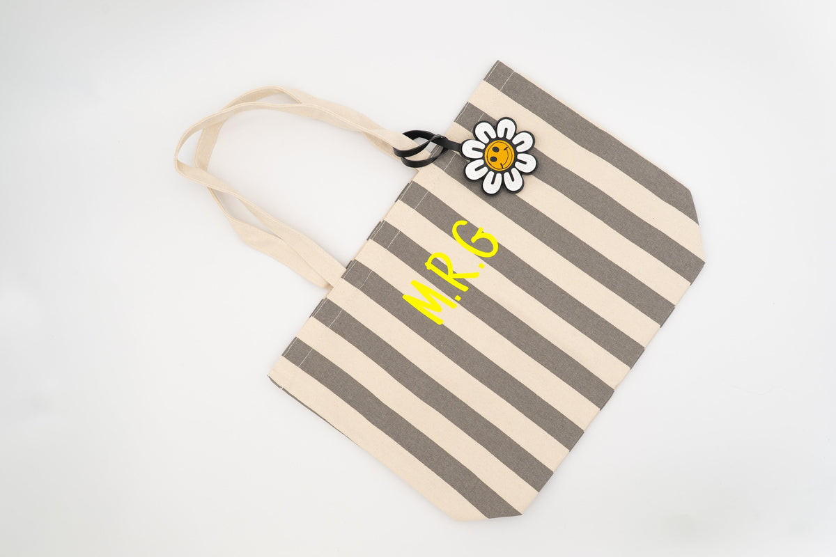 Grey and white striped pool bag decorated with a daisy charm