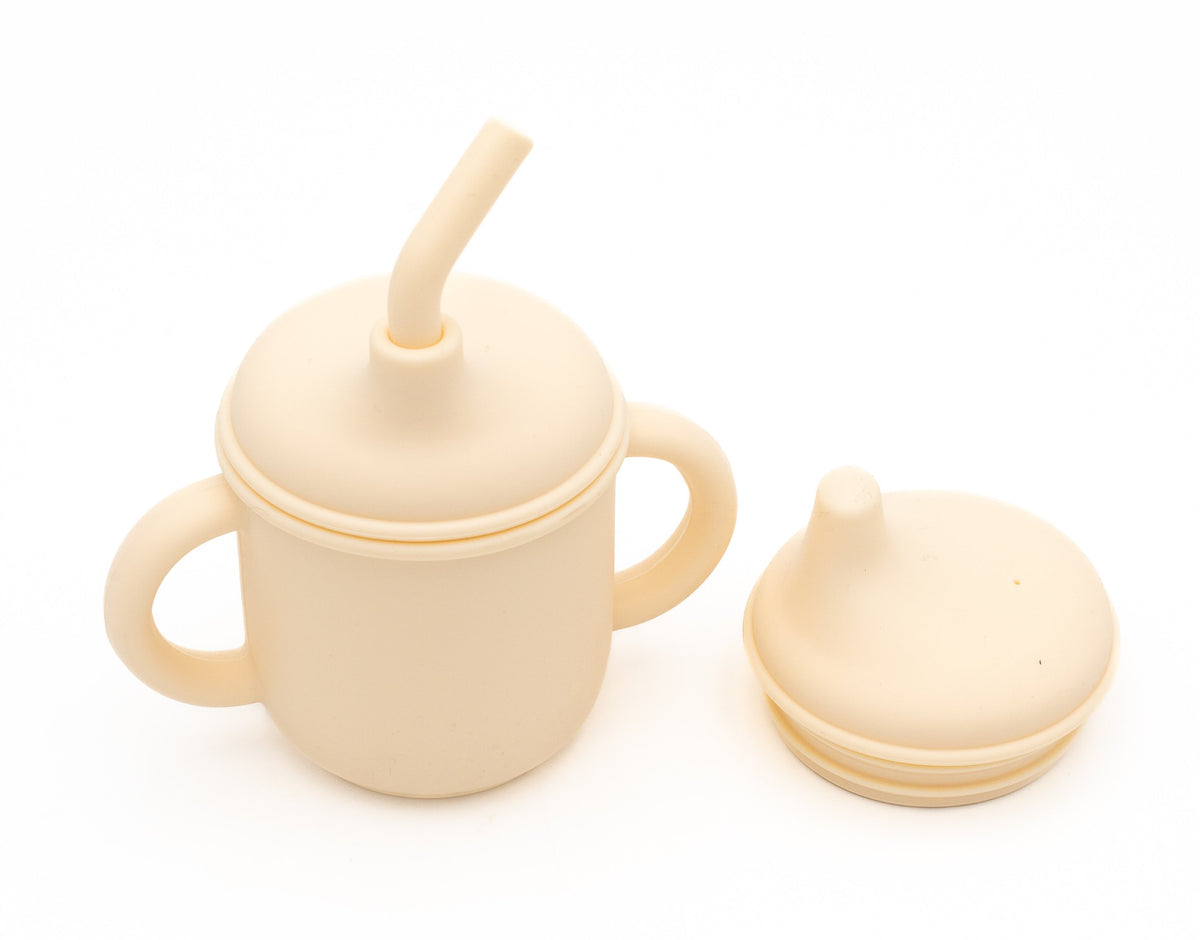 Cream-coloured cup with two drinking lids and a silicone straw