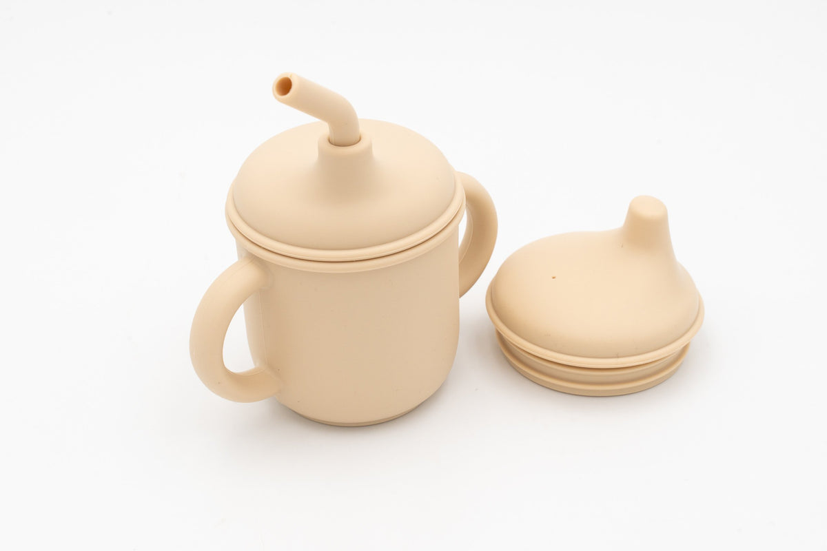 Open beige children's cup beside its two lids