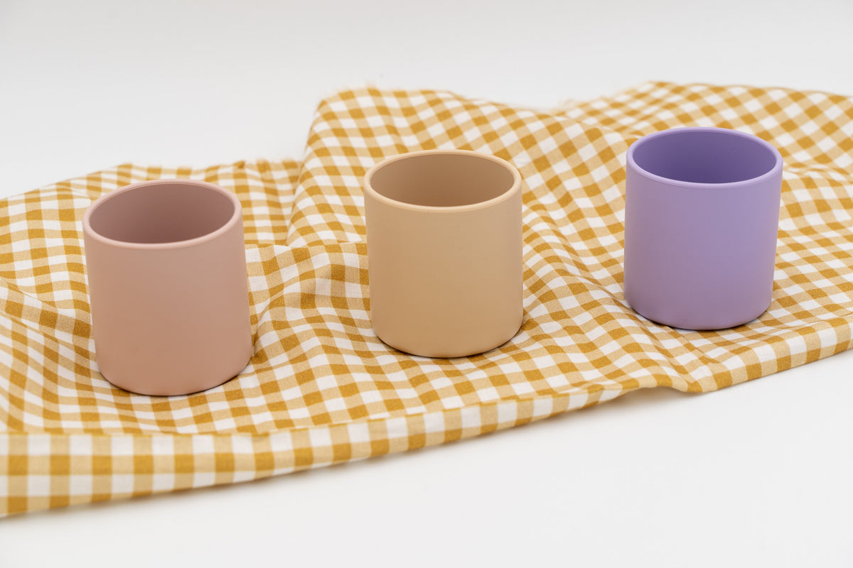 Three separate upright cups in pink, beige and lilac shades